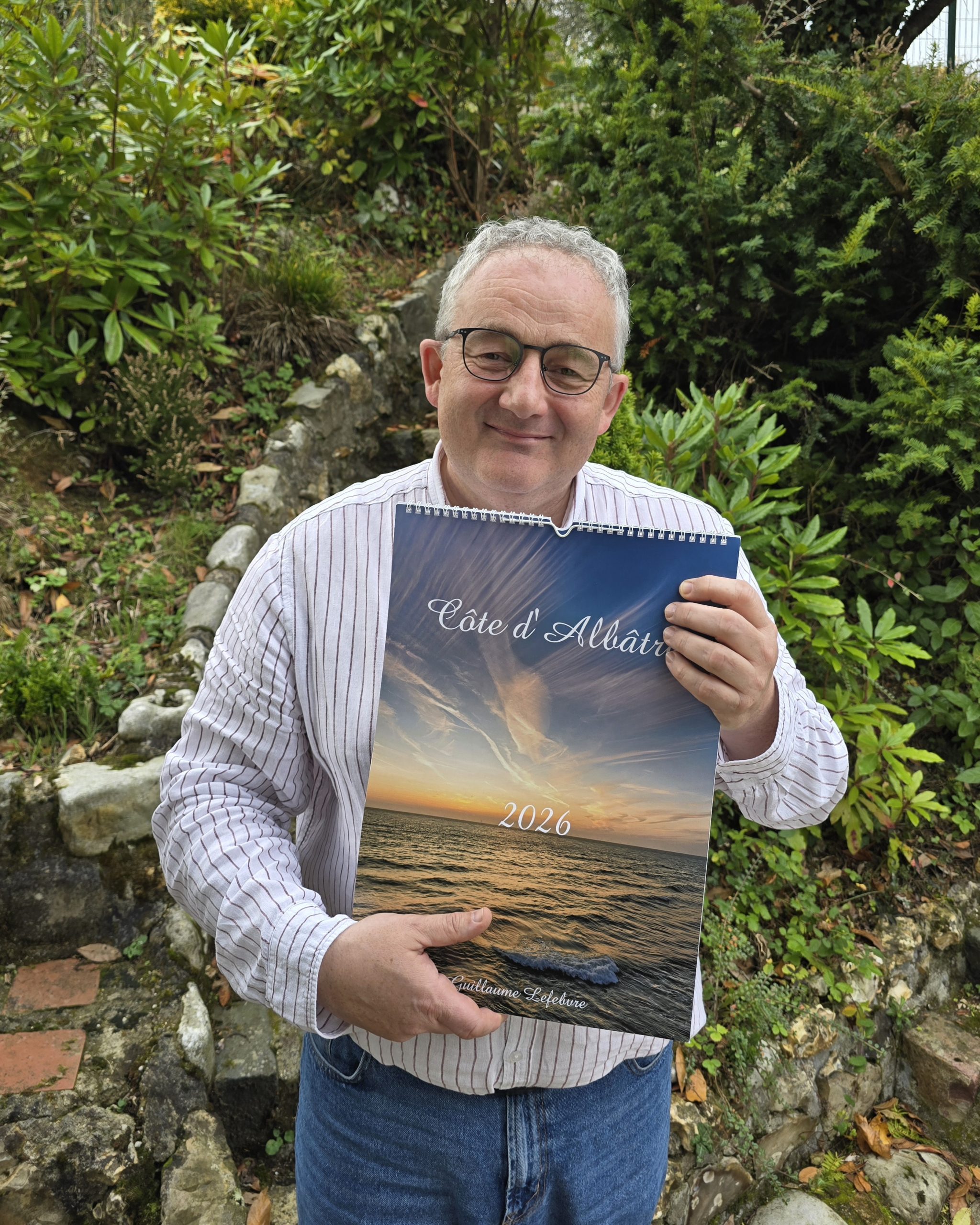 Photographe tenant dans ses mains son calendrier avec des photos de la côte d'albatre.